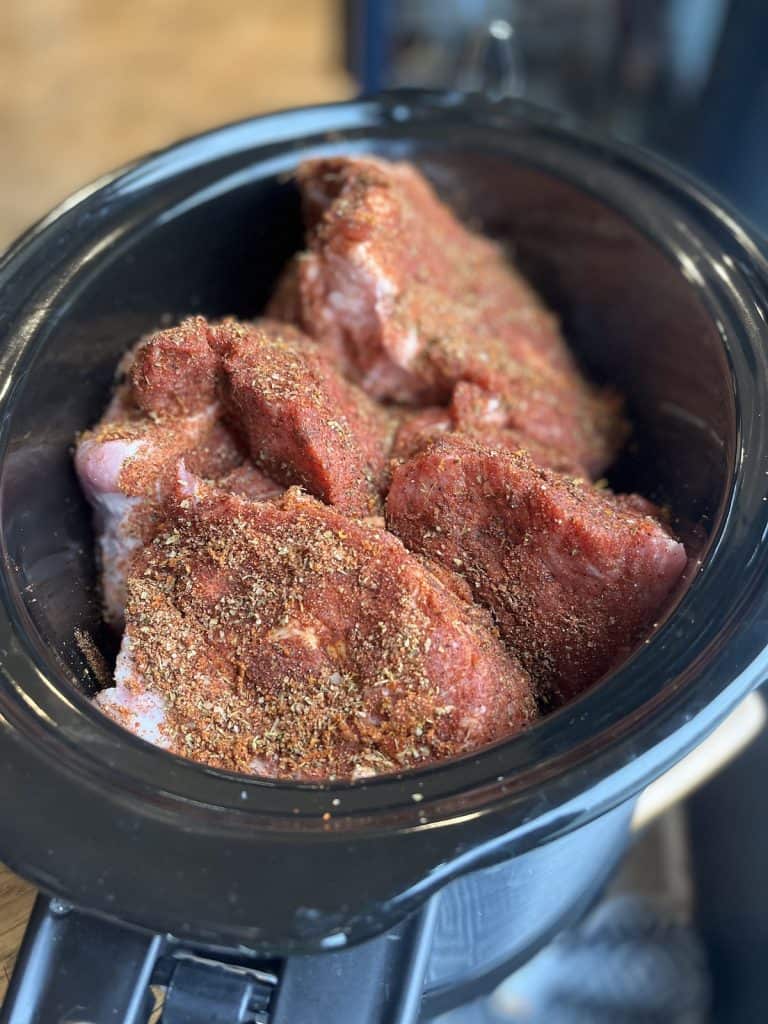 pork shoulder pieces of meat in a black crock pot