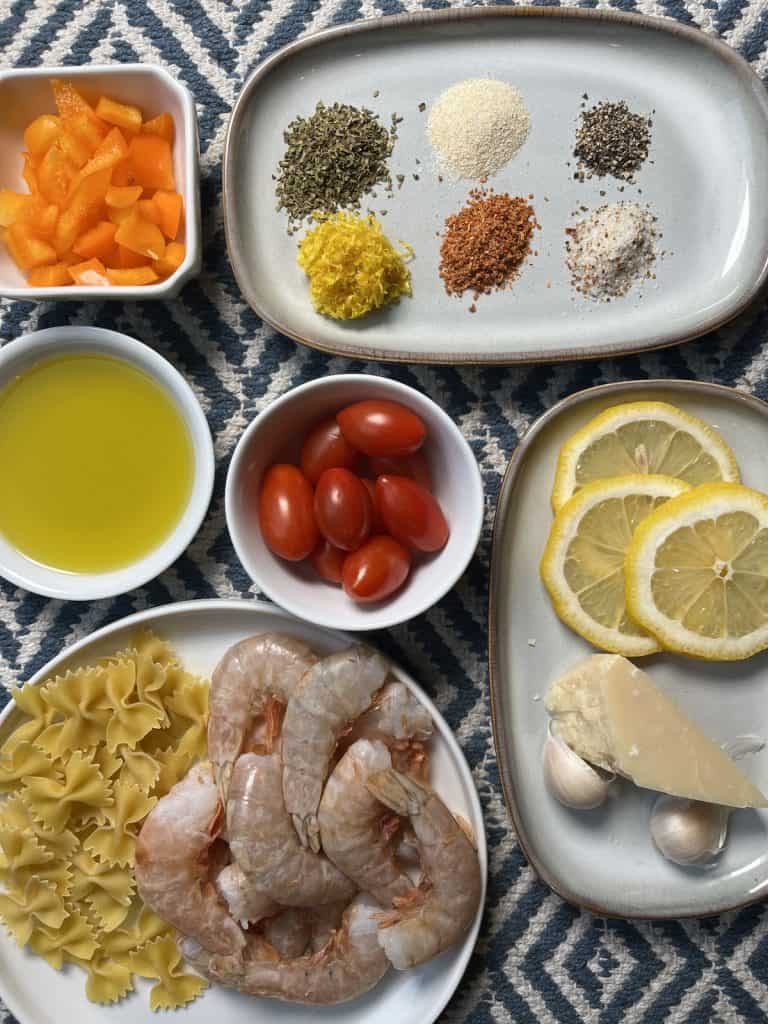spices, tomatoes, lemons, shrimp, oil, orange peppers in white dishes