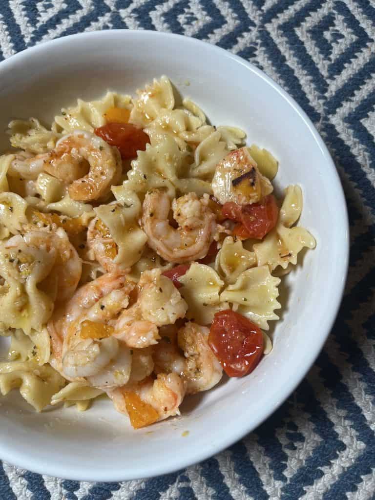 Shrimp with bow tie pasta, tomatoes, and peppers in a white bowl