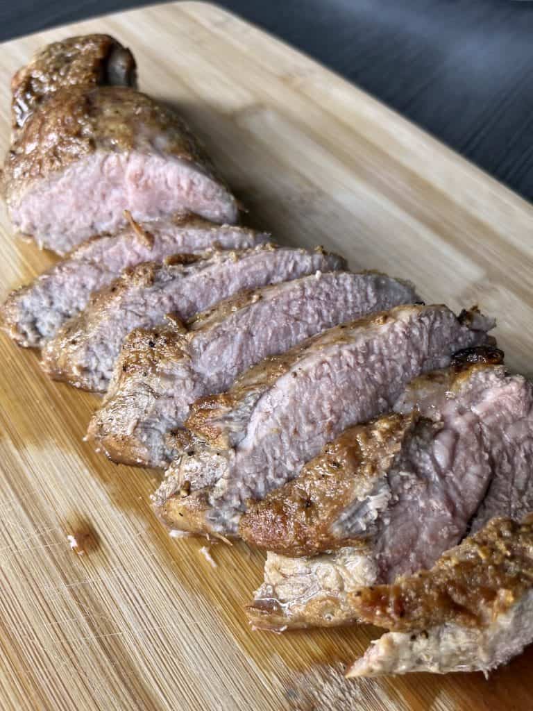 sliced pork tenderloin on wood cutting board