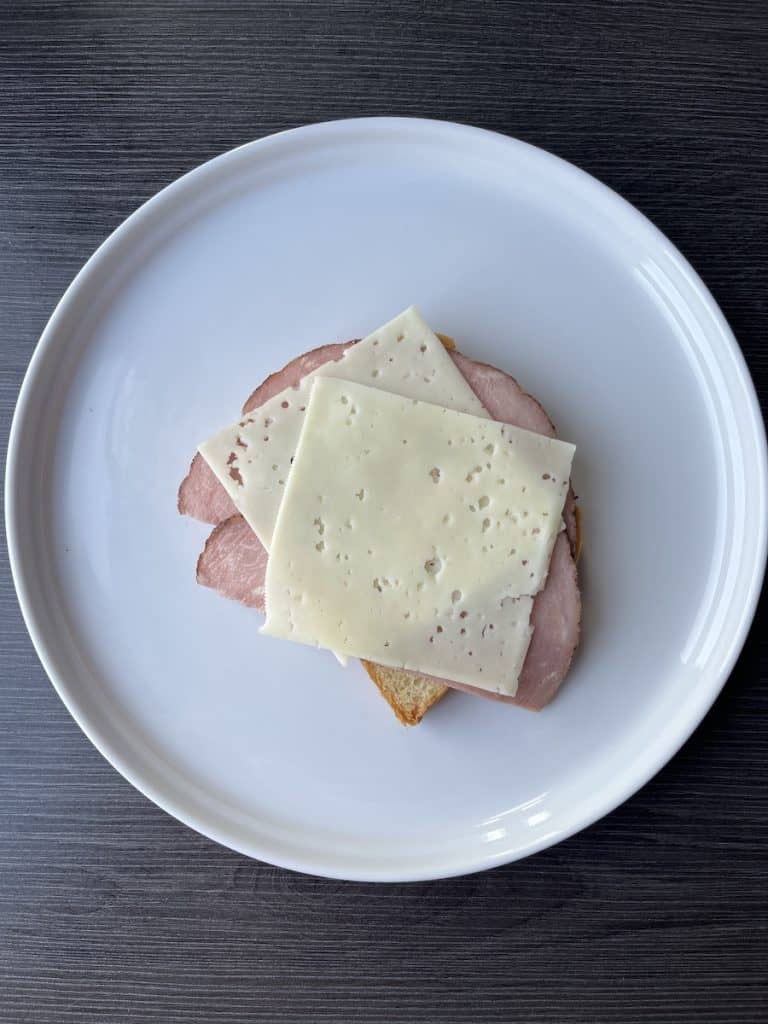 bread, ham, and cheese, layered on white plate
