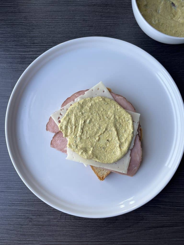 bread, ham, cheese and sauce layered on white plate