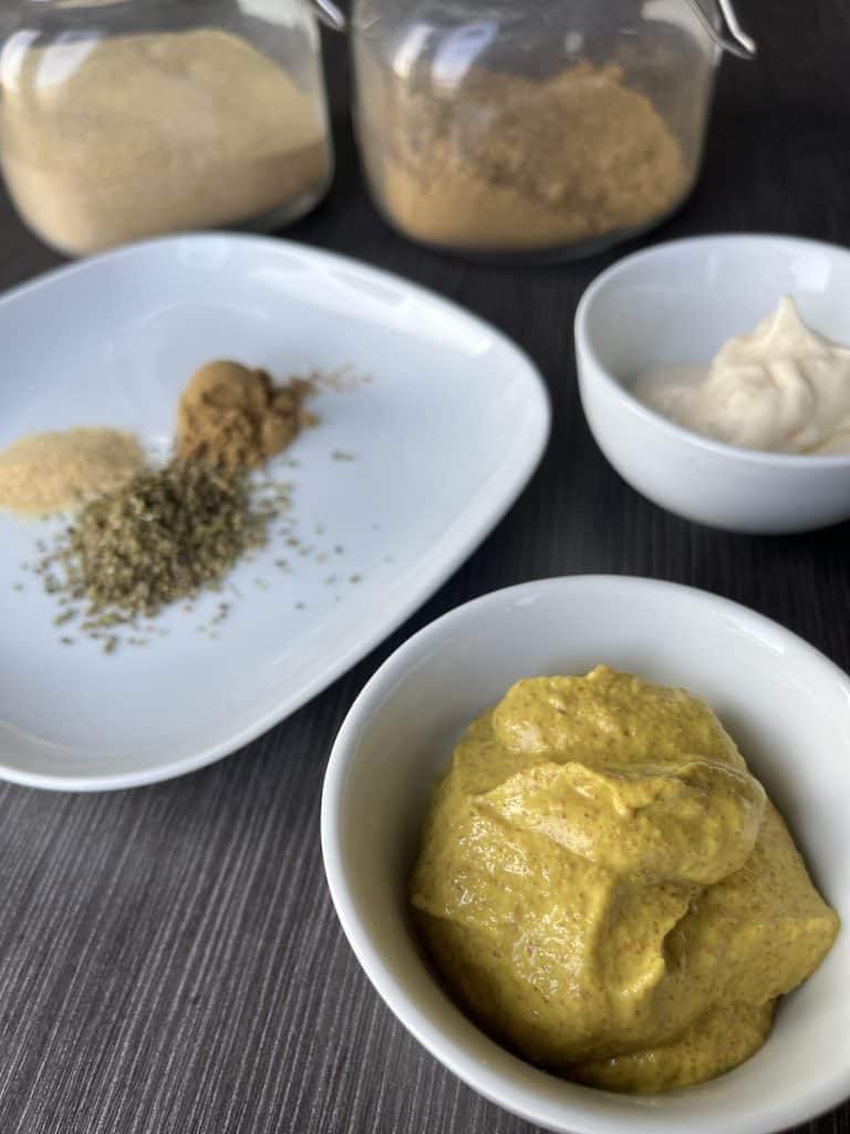 mustard, mayo and spices in white bowls to make cuban sandwich sauce