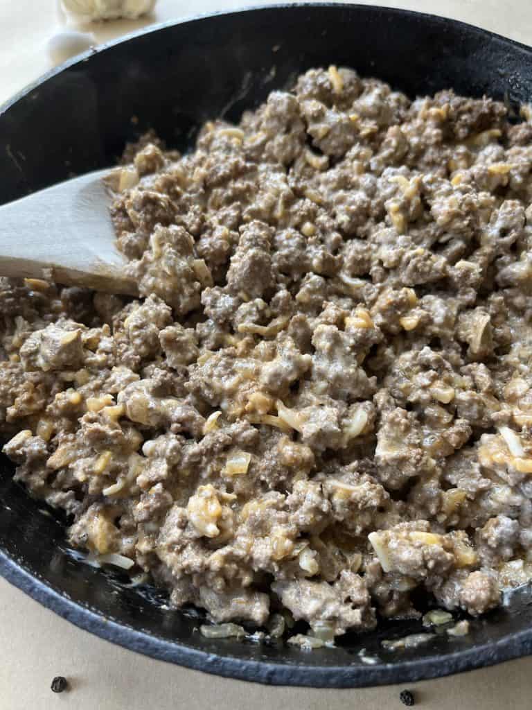 ground beef and cheese in a cast-iron skillet to make Beef Enchiladas with Flour Tortillas