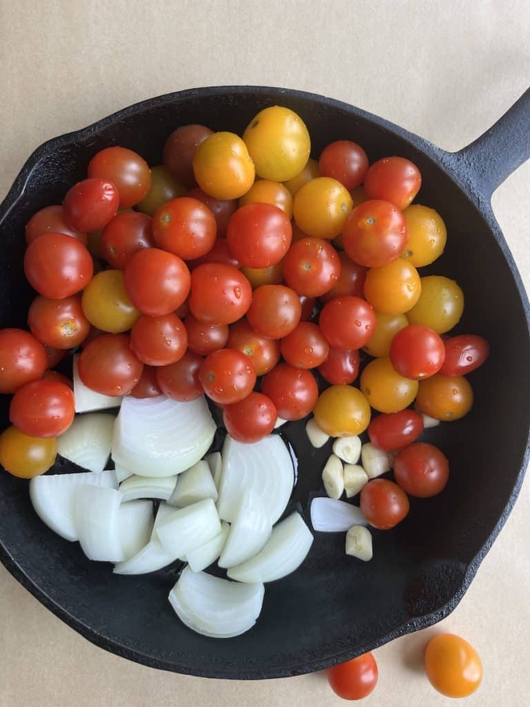 uncooked tomatoes, onions and spices in a cast-iron skillet