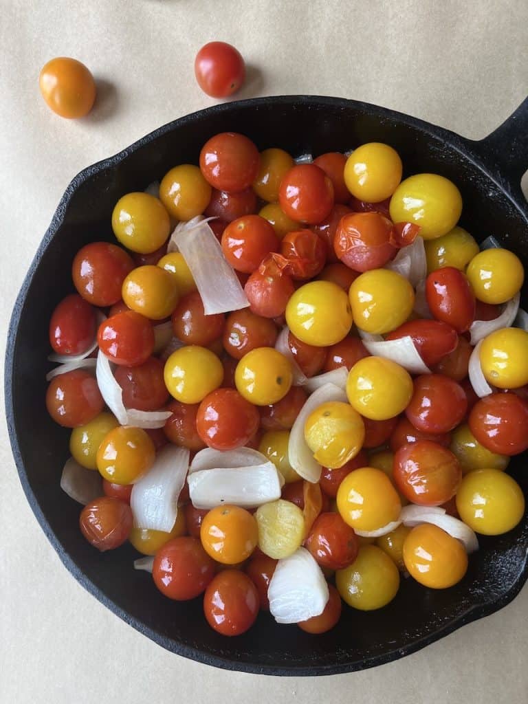 uncooked tomatoes, onions and spices in a cast-iron skillet