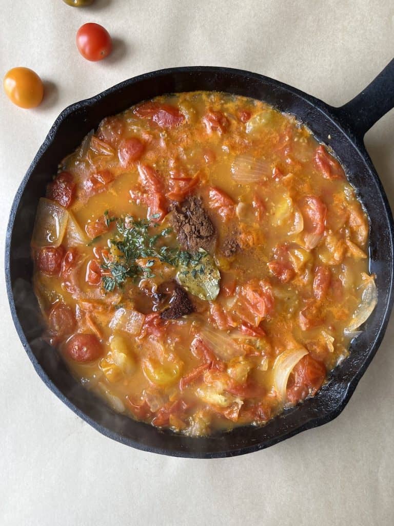 cooked tomatoes, onions and spices in a cast-iron skillet to make a sauce for Beef Enchiladas with Flour Tortillas