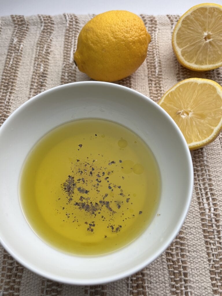 lemon juice, oil, salt and pepper, in a bowl with lemons in the background