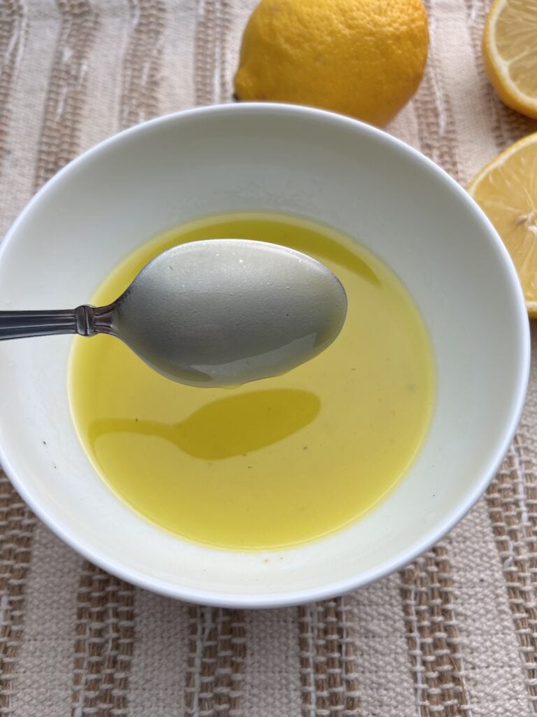 lemon vinaigrette dressing in a bowl with lemons in the background