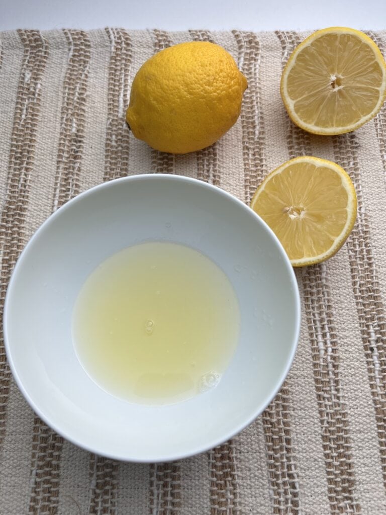 lemon juice in a bowl with lemons in the background