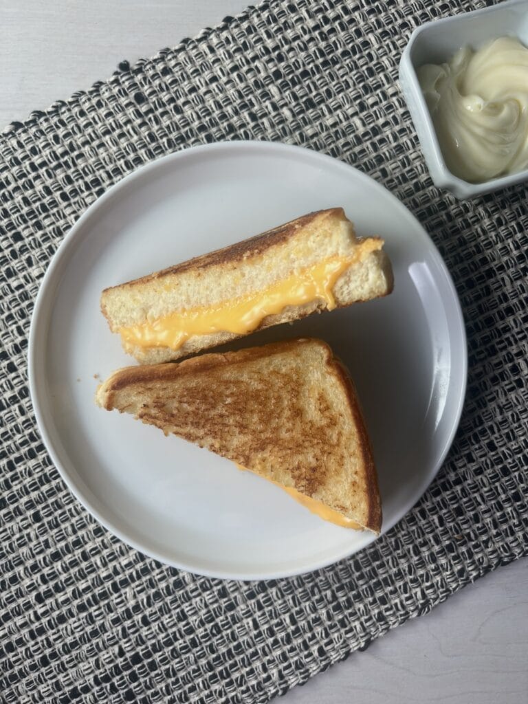 Texas toast grilled cheese sliced on a plate, butter in a bowl