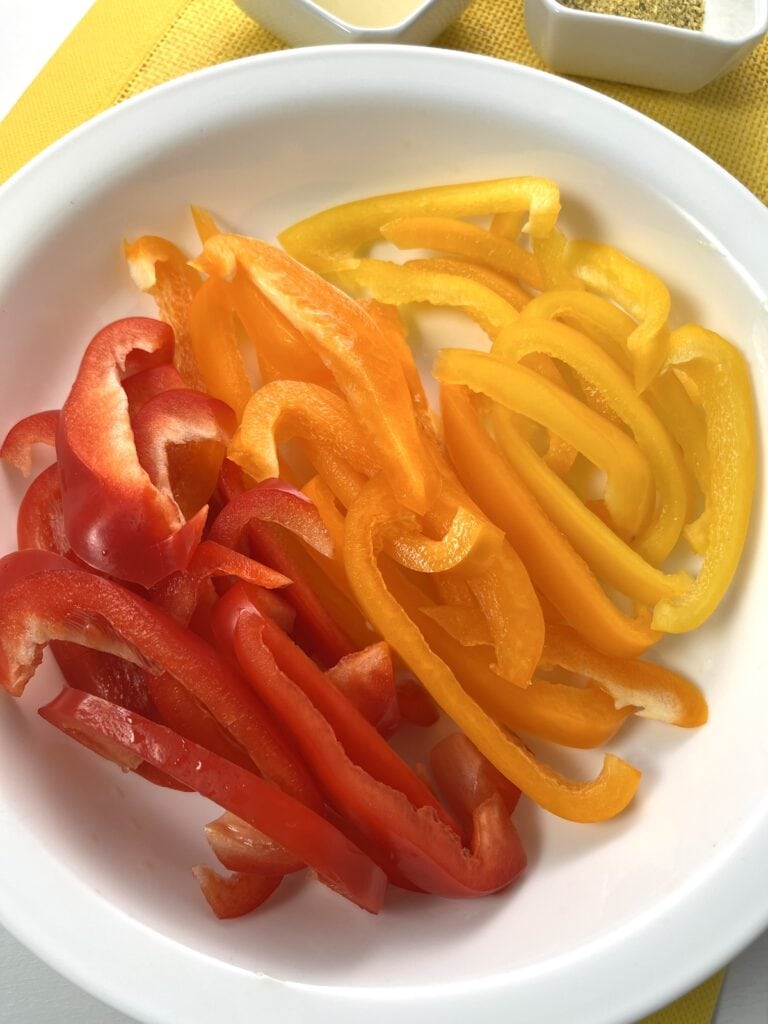sliced red, orange, and yellow bell peppers in bowl