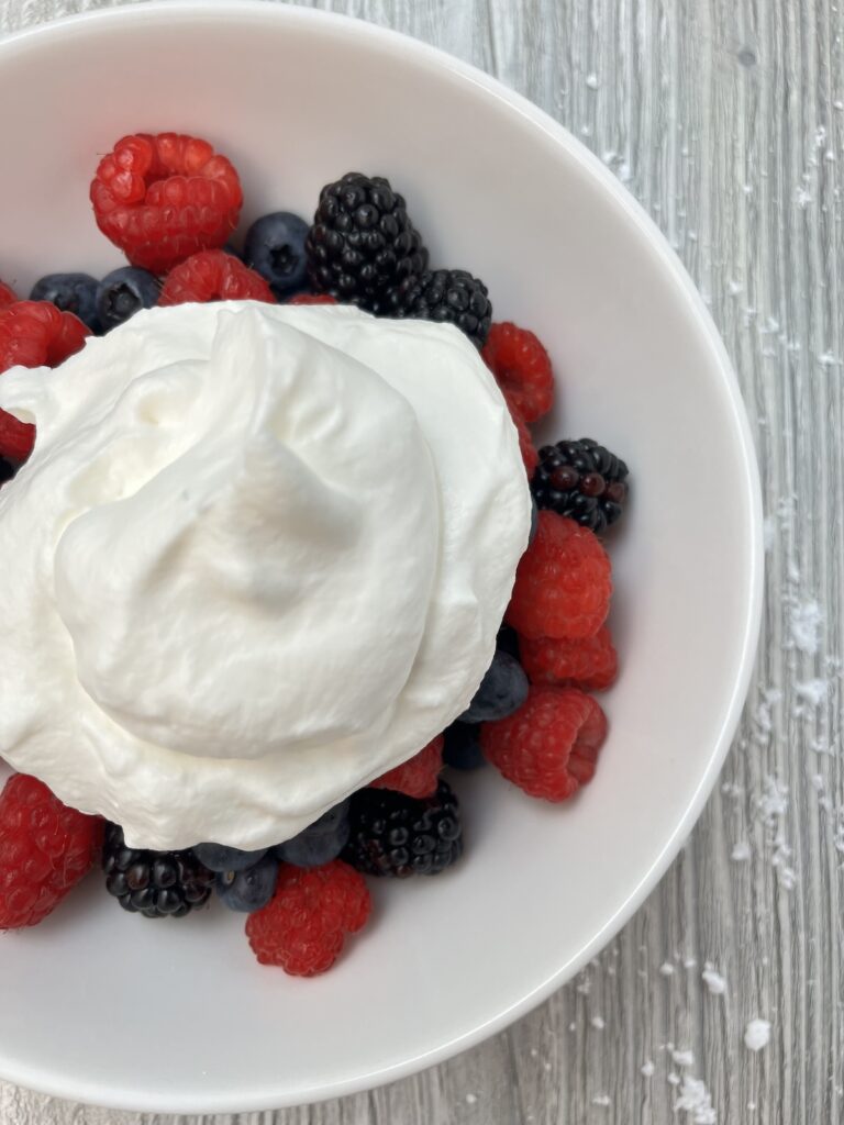 whipped cream over mixed berries in a bowl