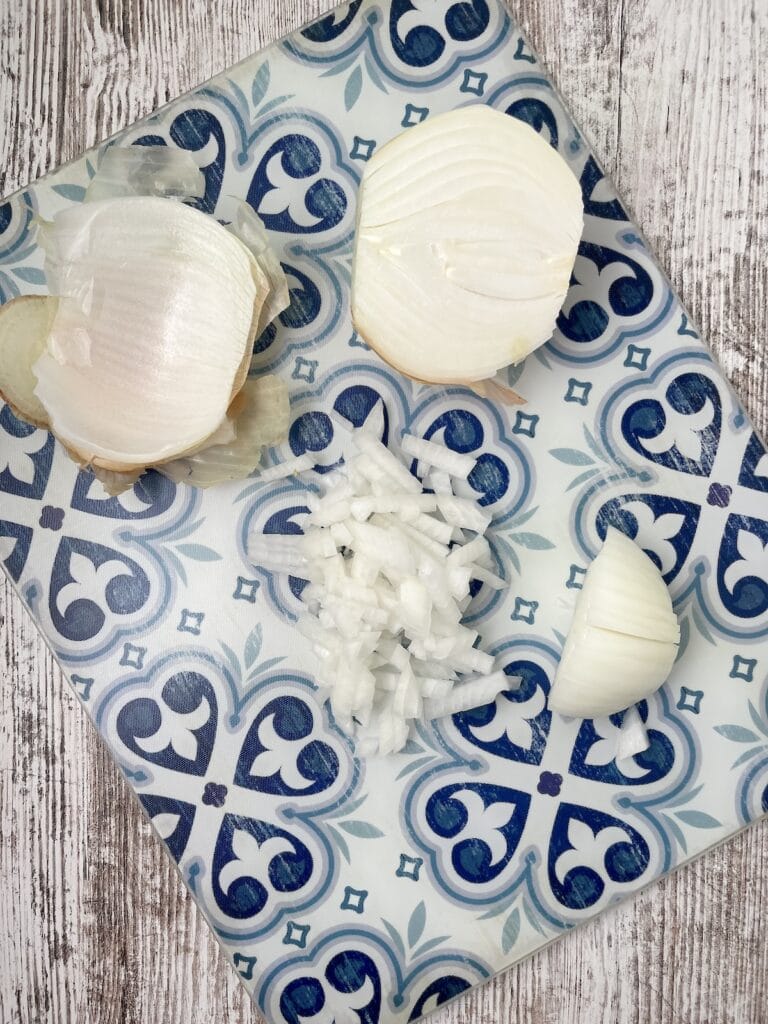 onion peels, half onion, sliced onion, and diced onions on a blue cutting board