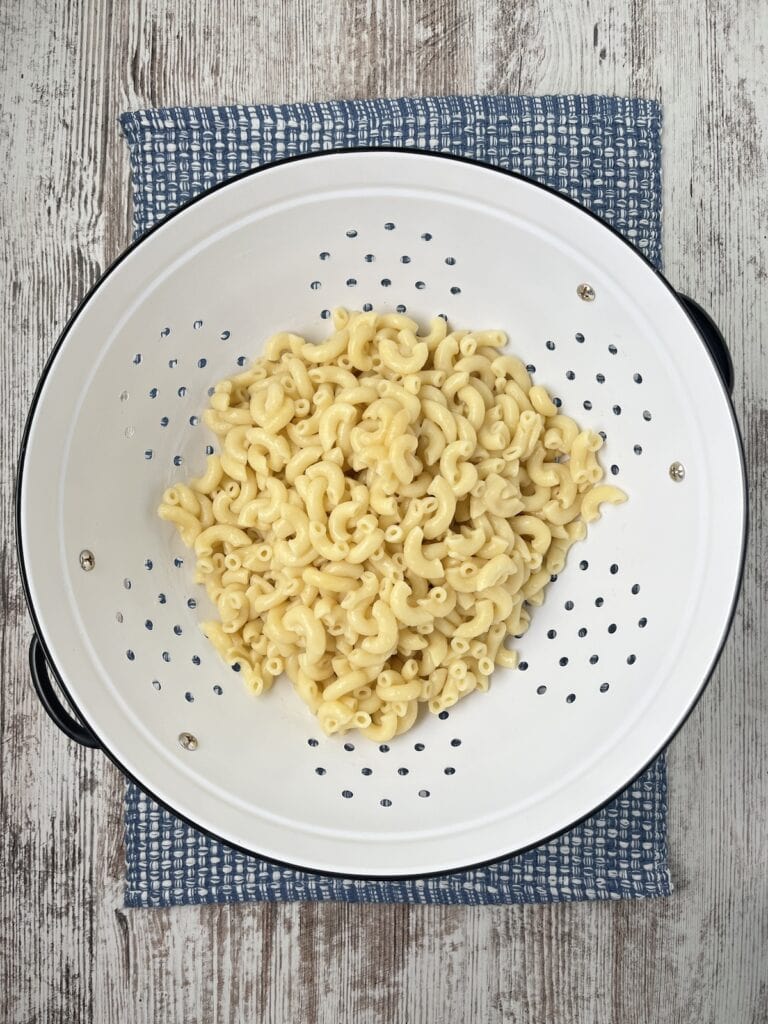 cooked pasta in a white metal strainer