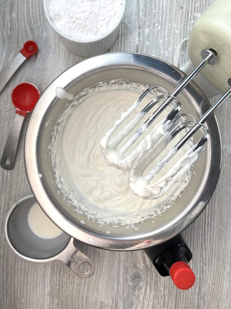 whipped cream in a bowl with a hand mixer