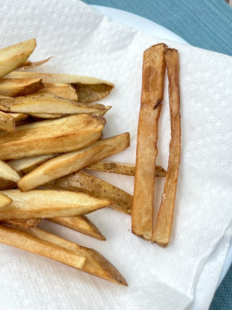 example of fries not cut evenly, dark and overcooked on a white paper towel