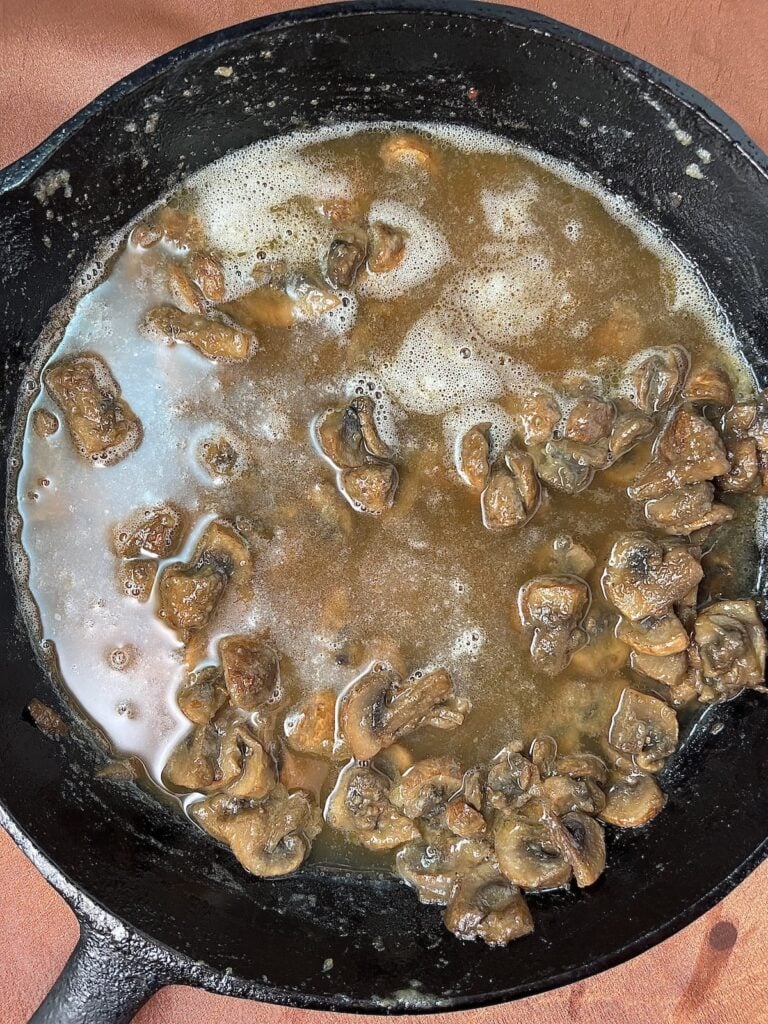 cooked mushrooms with marsala wine and beef broth in a skillet