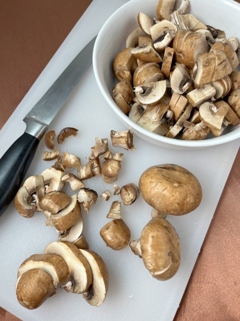 sliced baby bella mushrooms on a cutting board